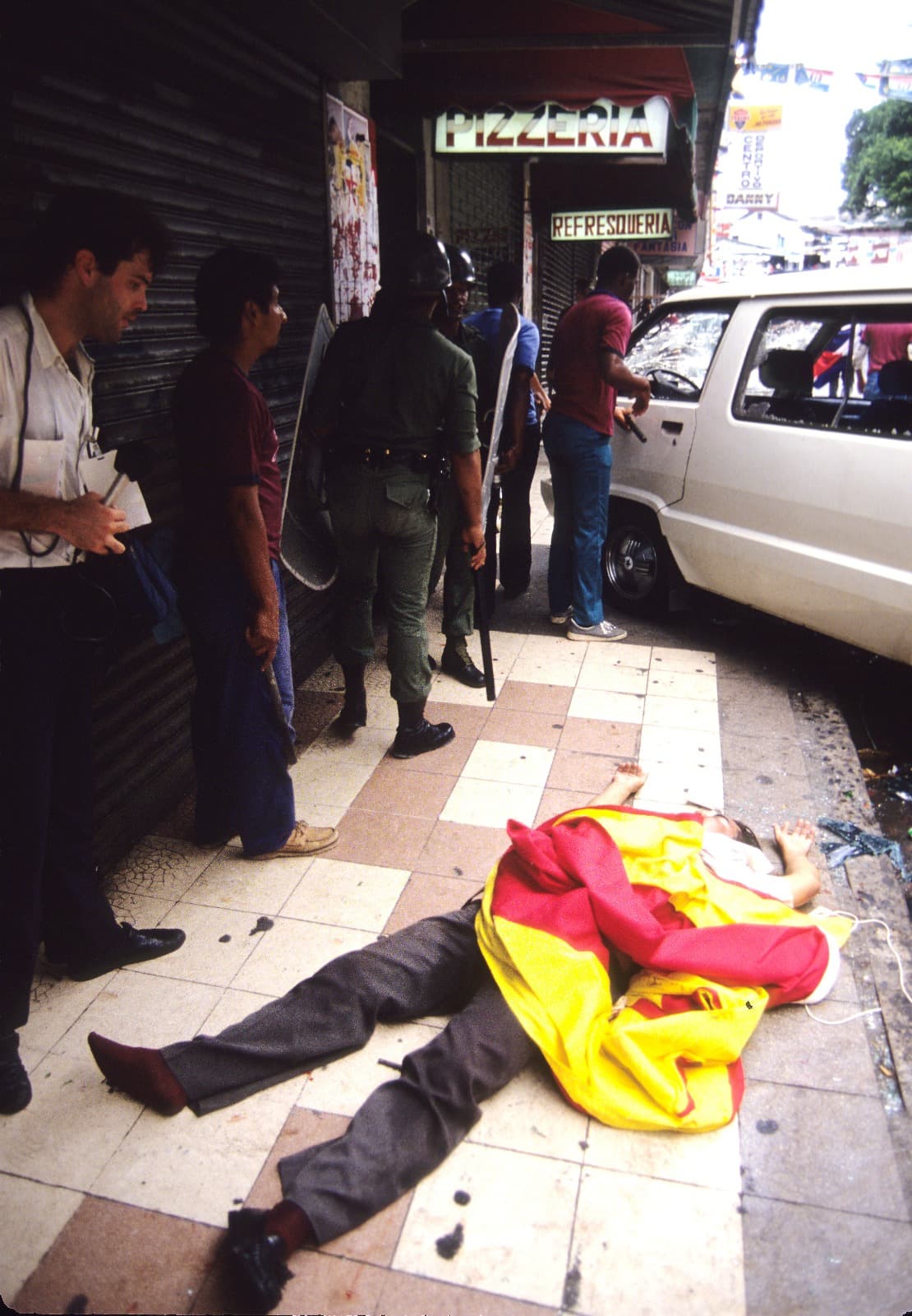Journalist David Adams (left) looks at the dead body of Manuel Guerra, a bodyguard for presidential candidate Guillermo Endara after pro-Noriega paramilitaries attacked an opposition march on May 10,1989.