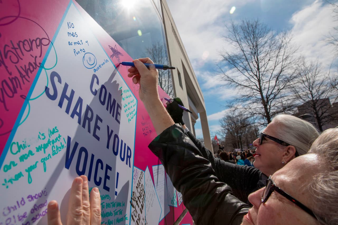 Algunos manifestantes se detienen para escribir mensajes a favor del control de armas en carteles dispuestos en la fachada del Newseum de Washington DC.