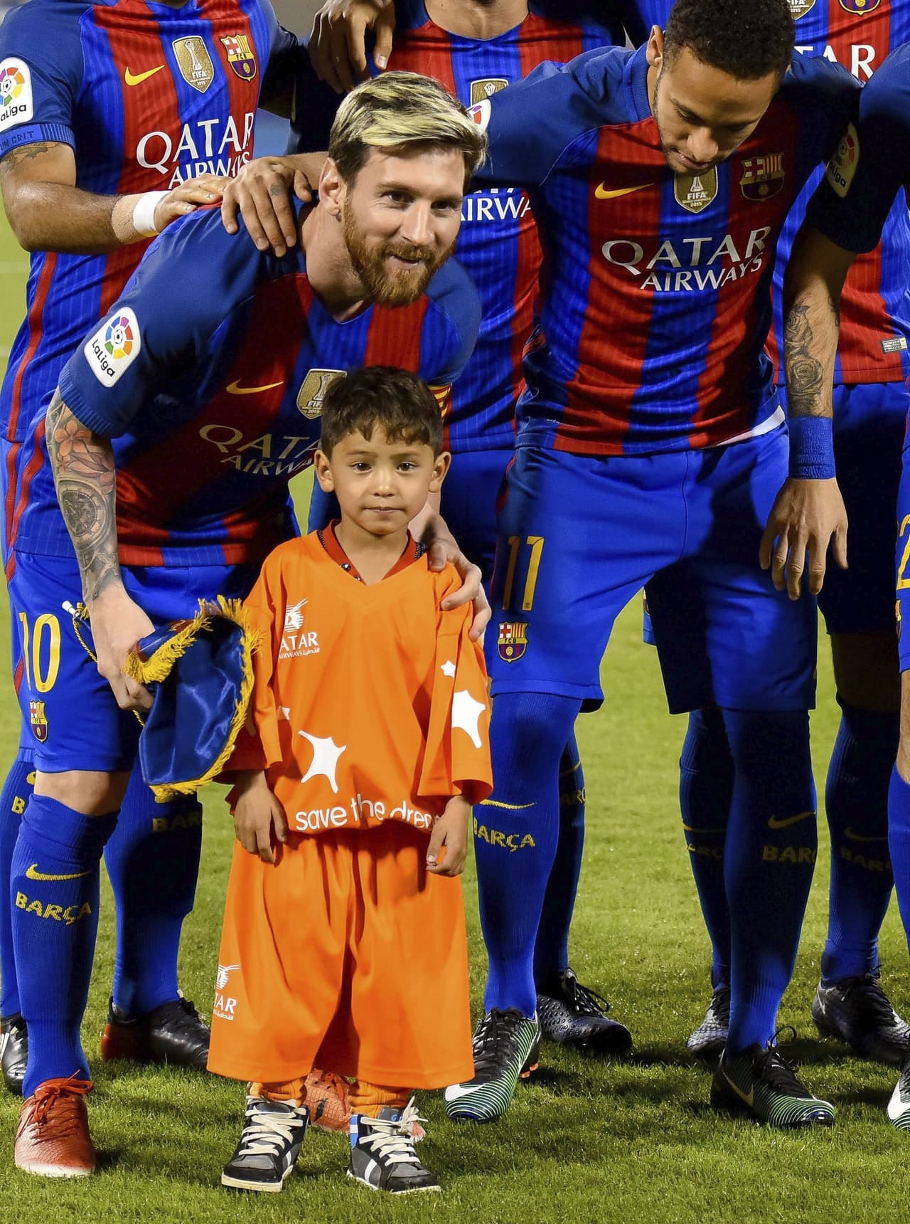 El delantero argentino del Barcelona Lionel Messi (i) y el delantero brasileño Neymar (d) posan con el niño afgano Murtaza Ahmadi (c), en el estadio Thani Bin Jassim, en Doha, Catar.