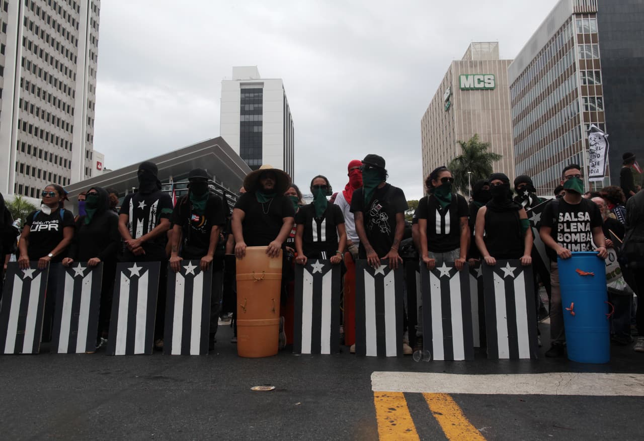 Un grupo marcha con un ataúd y banderas de Puerto Rico pintadas de negro. (Reuters)