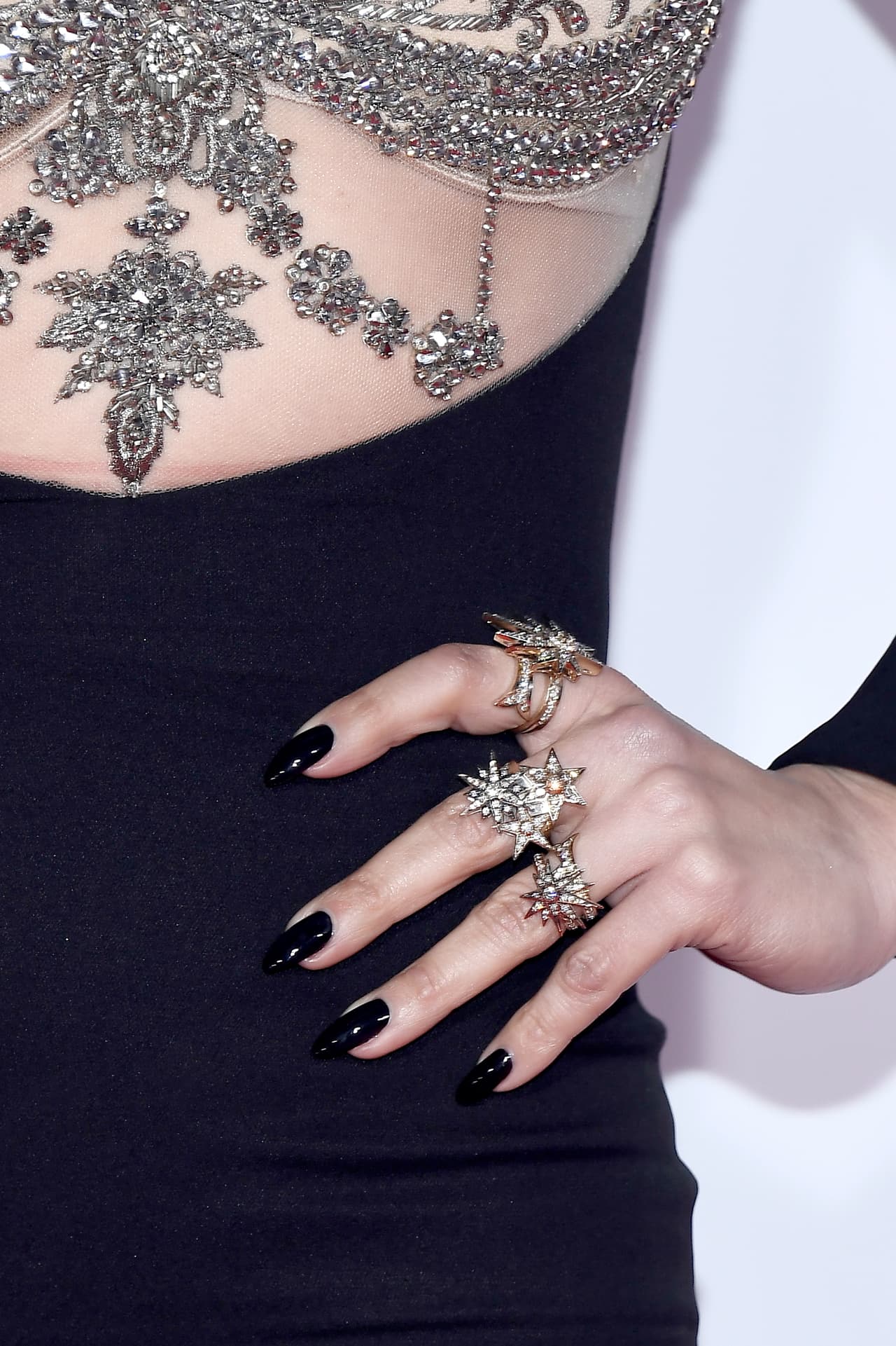 Para resaltar los anillos en oro y diamantes valuados en $60,000 dólares, la cantante eligió un manicure oscuro.