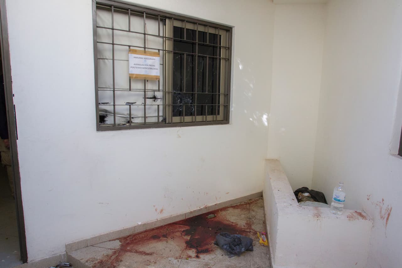 Otro charco de sangre junto a una ventana en la que se lee un aviso de las autoridades.