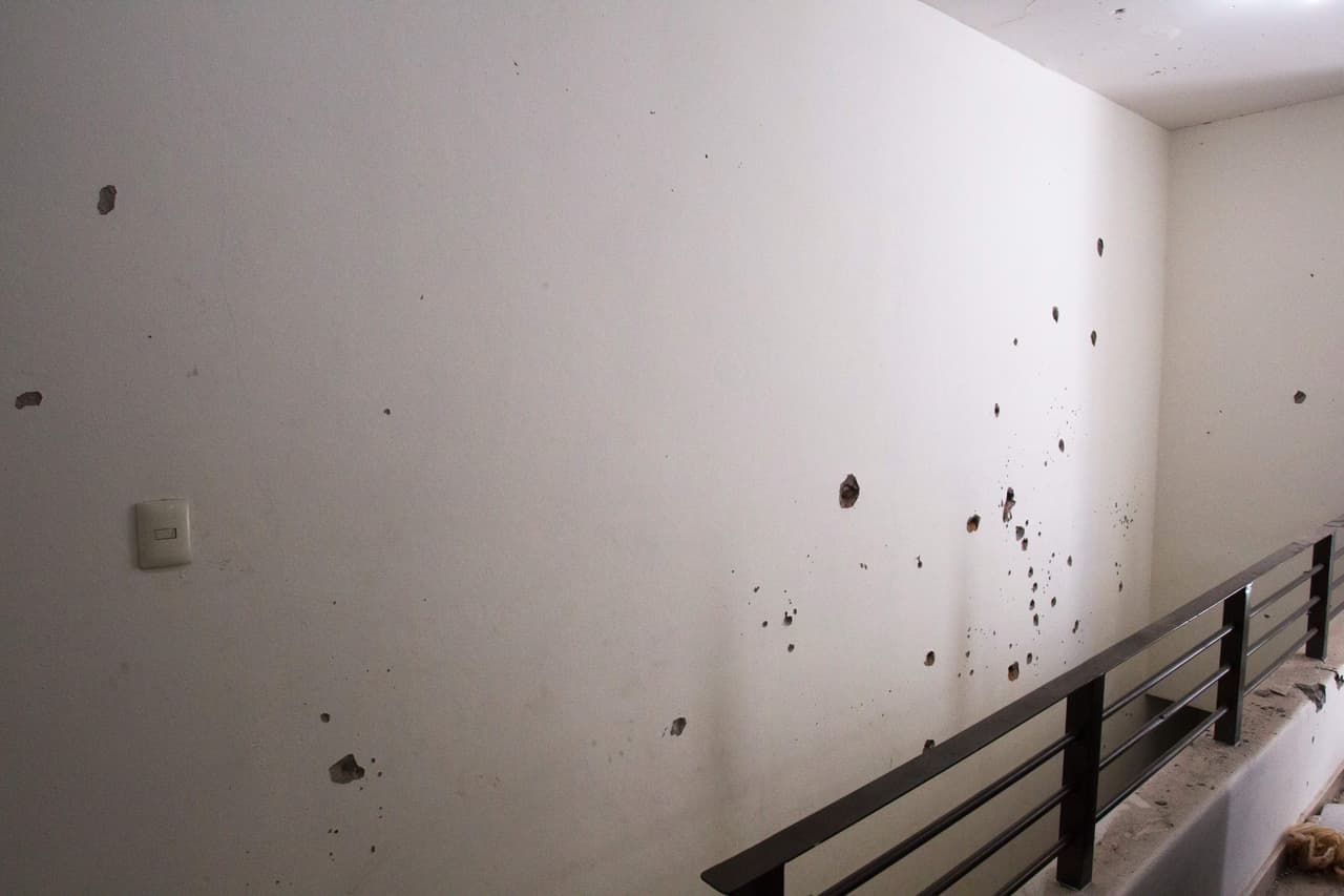 Un pasillo en el interior de la casa muestra los agujeros hechos por las balas sobre la pared.