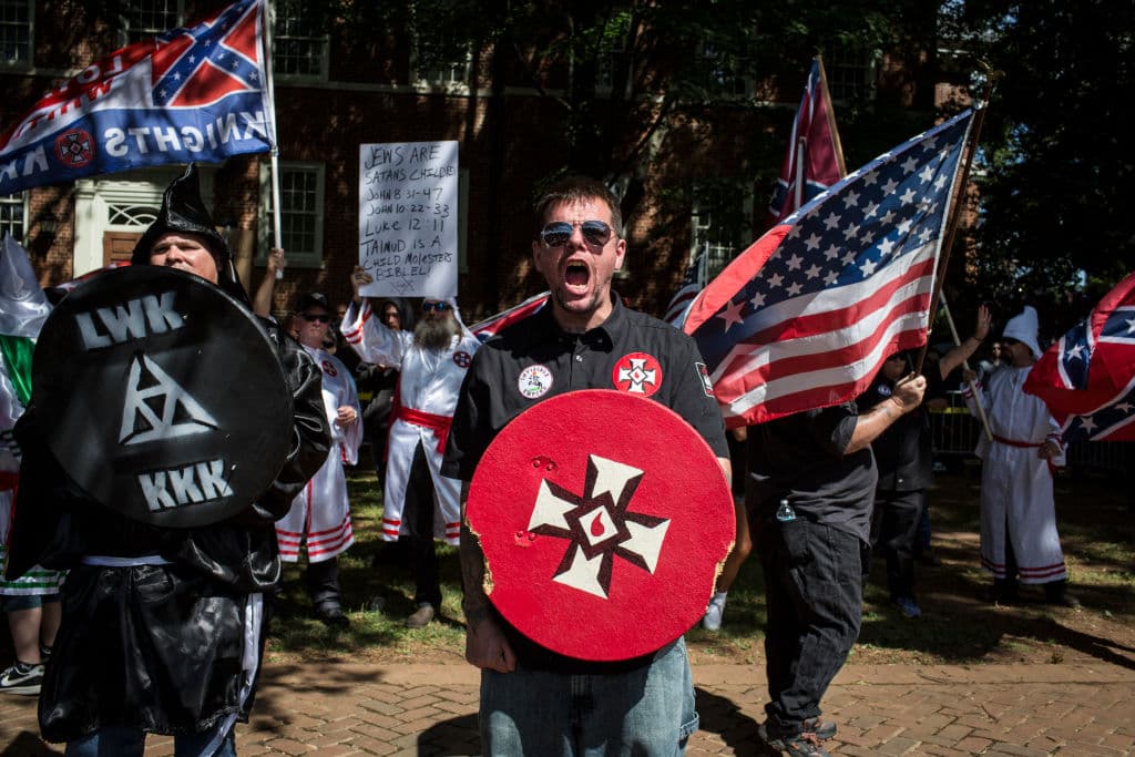 Members of the Ku Klux Klan of North Carolina wore suits and waved Confederate flags to protest the city's plan to remove a statue of Confederate General Robert E. Lee from a park.