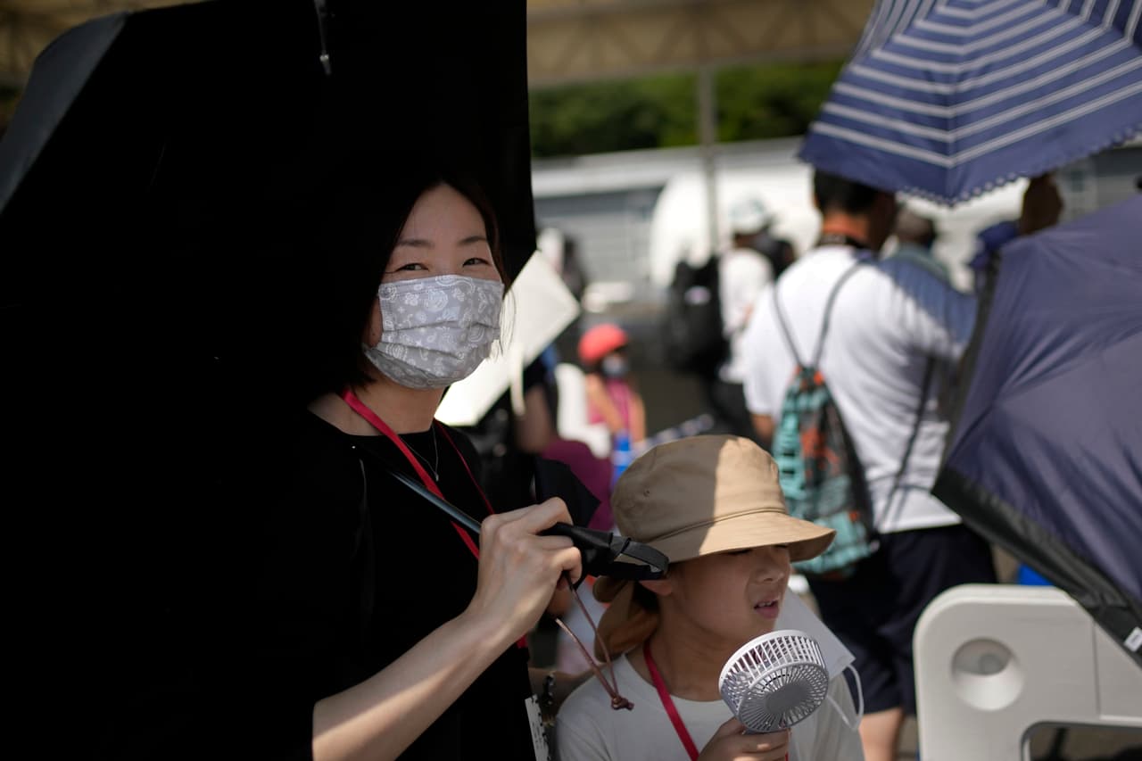 Algunos aficionados se las han ingeniado para dar un vistazo a la pista de patinaje, o ver eventos al aire libre, como el triatlón. En la imagen, una mujer entre la multitud que mira una competición de ciclismo femenil en
<a href="https://www.univision.com/temas/tokio-2020">Tokio</a>.