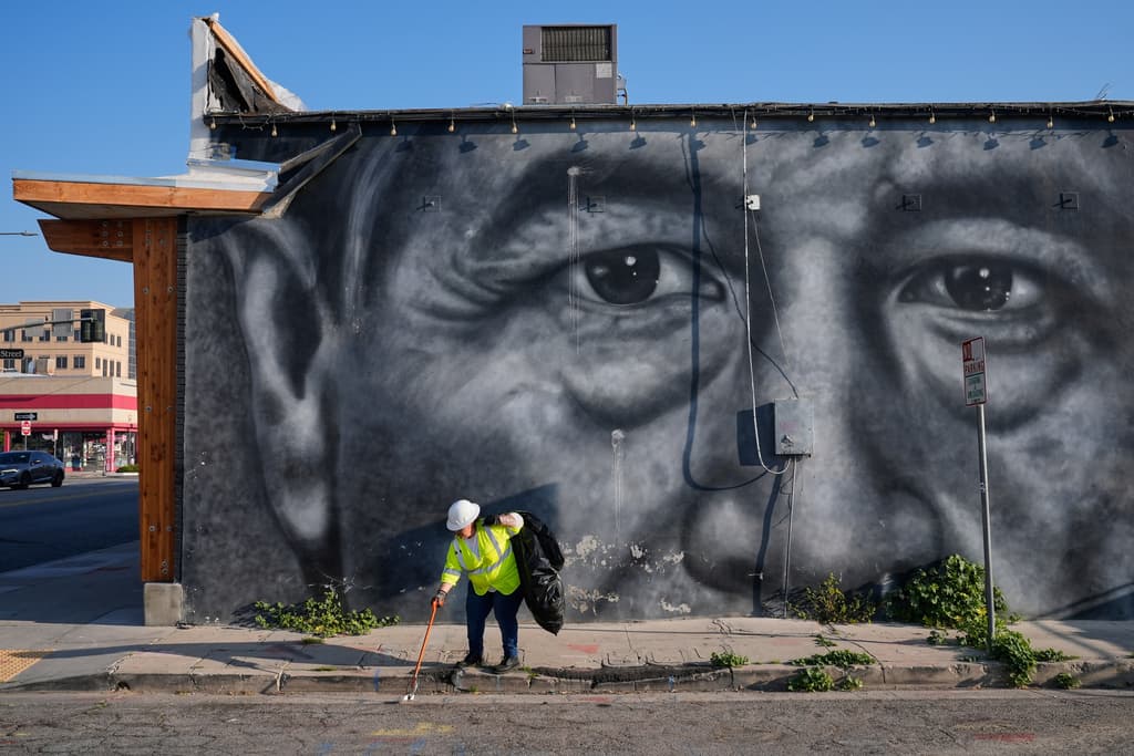 Un trabajador de limpieza recoge basura junto a un mural de César Chávez en Bakersfield, California, el jueves 19 de marzo de 2026.