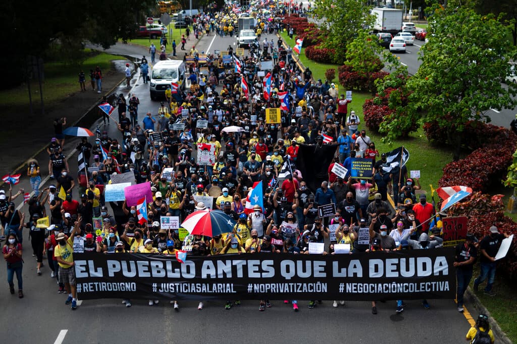 La multitud aplaudía mientras los manifestantes sostenían carteles que exigían salarios justos.
<br>