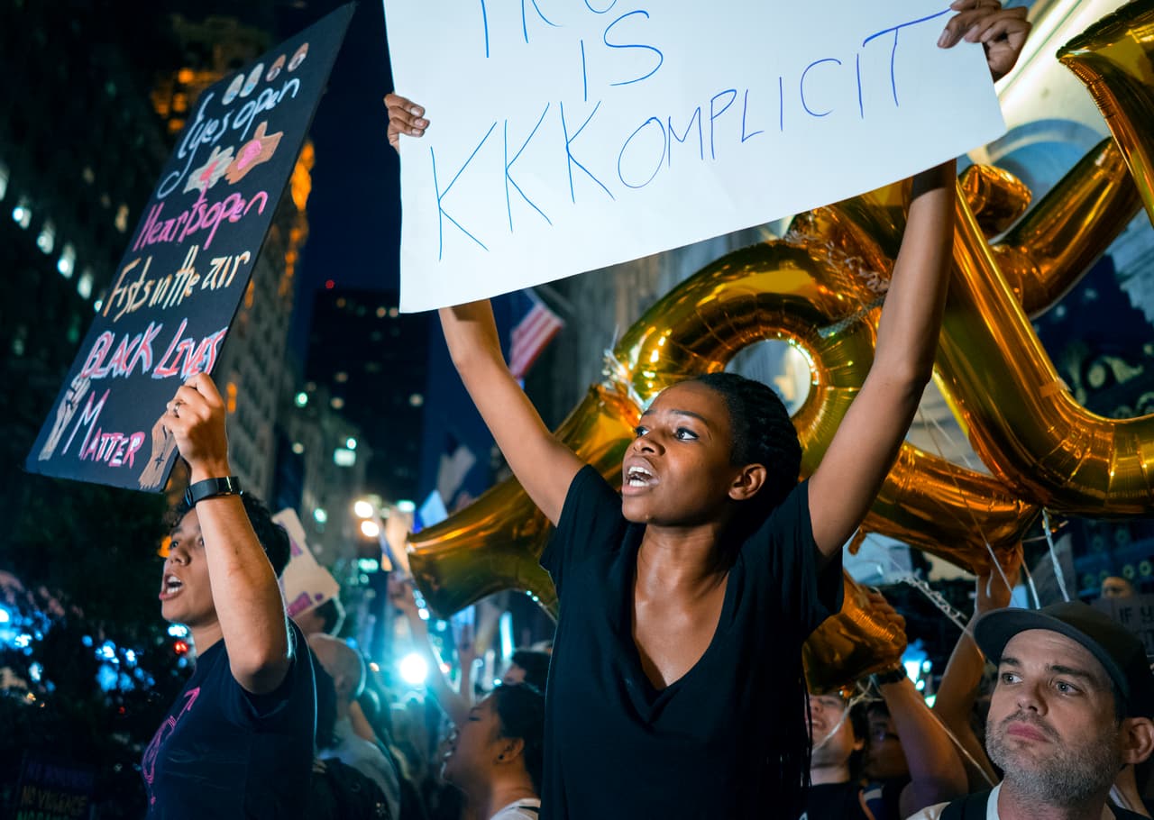 Trump tuvo un duro recibimiento en su ciudad en medio de las protestas en contra del racismo y los supremacistas. Las manifestaciones fueron en parte alentadas por
<b><a href="http://www.univision.com/noticias/incidentes-de-odio/con-dos-dias-de-retraso-y-tras-fuertes-criticas-trump-condena-el-racismo-a-los-supremacistas-y-al-kkk-por-la-violencia-en-charlottesville">su reacción inicial el sábado al ataque de un supremacista blanco</a></b> que mató con su auto a una mujer y dejó a otras 35 personas heridas. Ese día, el mandatario solo condenó "la violencia que se da desde muchos lados" sin mencionar específicamente a los supremacistas blancos. (Craig Ruttle/AP)