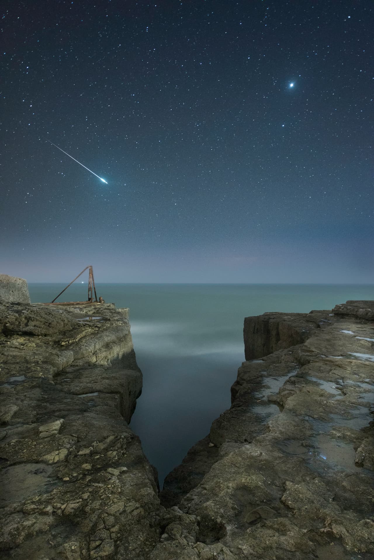 Júpiter y una estrella fugaz. Se ve la estela de una estrella fugaz atravesando el cielo sobre Portland, en DOrset, UK. A la derecha de la imagen también se destaca el brillo de Júpiter.