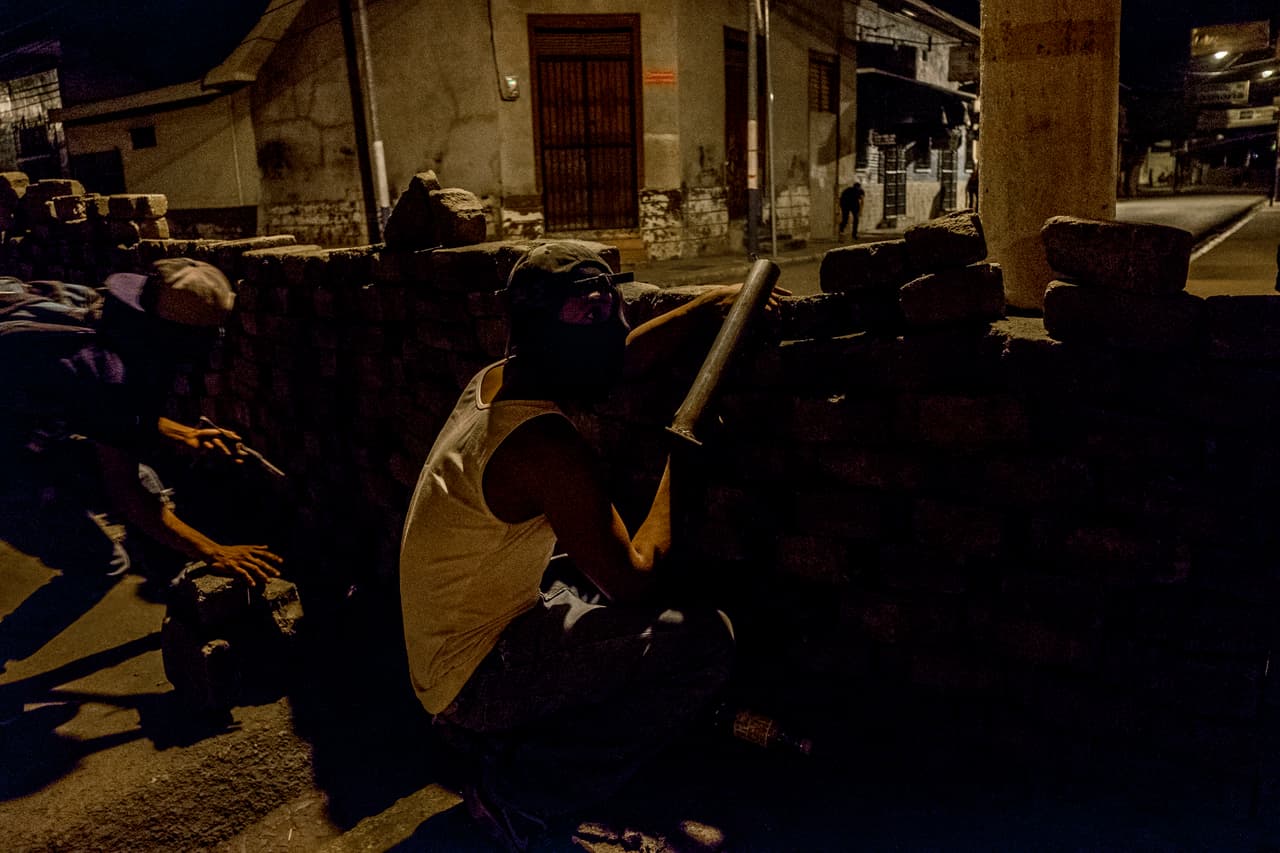 Masked citizens take cover in a barricade as they confronts the police with non lethal self made “mortar” to defend their selfs in Masaya, Nicaragua. June 12 2018.