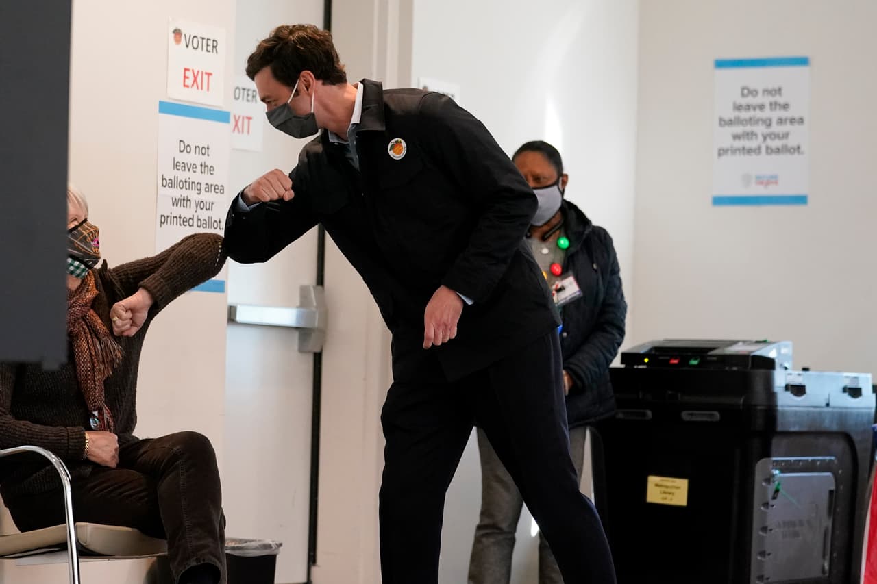 El candidato demócrata para el Senado de los Estados Unidos de Georgia, 
<a href="https://www.univision.com/local/atlanta-wuvg/elecciones-estados-unidos-2020/jon-ossoff-el-periodista-investigativo-que-quiere-llegar-al-senado-para-luchar-por-la-justicia">Jon Ossoff</a>, saluda a un trabajador electoral después de emitir su voto temprano el pasado 22 de diciembre en Atlanta. Por segunda vez en tres años, Ossoff está haciendo campaña en horas extras. El demócrata de 33 años busca la silla del senador republicano 
<a href="https://www.univision.com/local/atlanta-wuvg/elecciones-estados-unidos-2020/david-perdue-senador-georgia-seguidor-de-trump-reeleccion">David Perdue</a>.