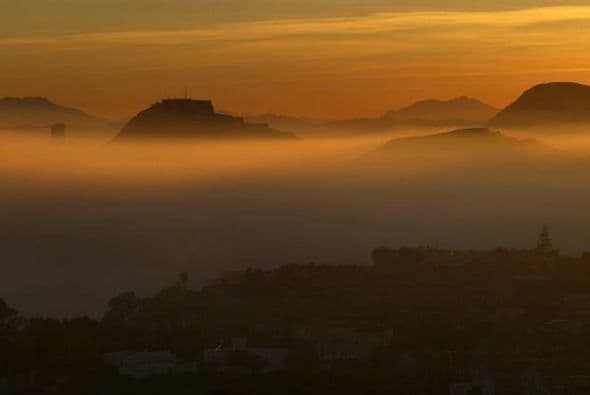 El Castillo de Santa Bárbara asoma al anochecer entre el mar de bruma que ha cubierto la ciudad de Alicante.