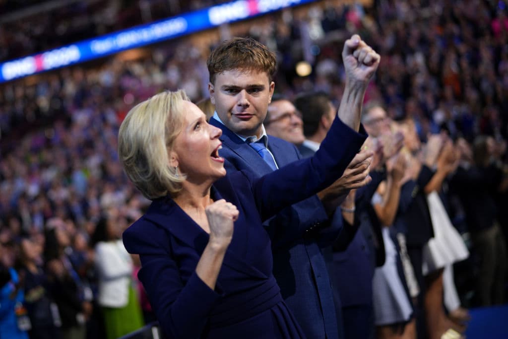 Tim Walz entra al escenario de la Convención Demócrata. Su esposa, la primera dama de Minnesota, Gwen Walz, y su hijo Gus Walz observan desde el público.