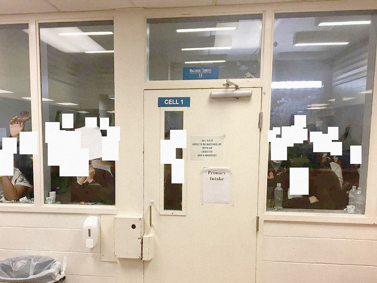 Esta imagen muestra otra de las 
<b>celdas diseñada para recluir a solo 35 detenidos hombres</b> para que esperen ahí mientras son procesados por los agentes de CBP. Sin embargo, en la fecha en la que la Oficina del Inspector General realizó el recorrido 
<b>había 155 inmigrantes indocumentados arrestados solo en ese espacio.</b> Los cuadros blancos resguardan los rostros de estas personas. Aseguran que la sobrepoblación ha hecho que incluso en alguna celda vieran a personas paradas sobre el inodoro para hacer espacio para que ingresen más personas o sencillamente para poder respirar.