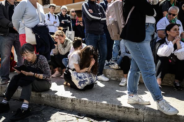 Un grupo de creyentes católicos rezan sentados en la calle Via della Conciliazione, que va hacia la plaza de San Pedro.