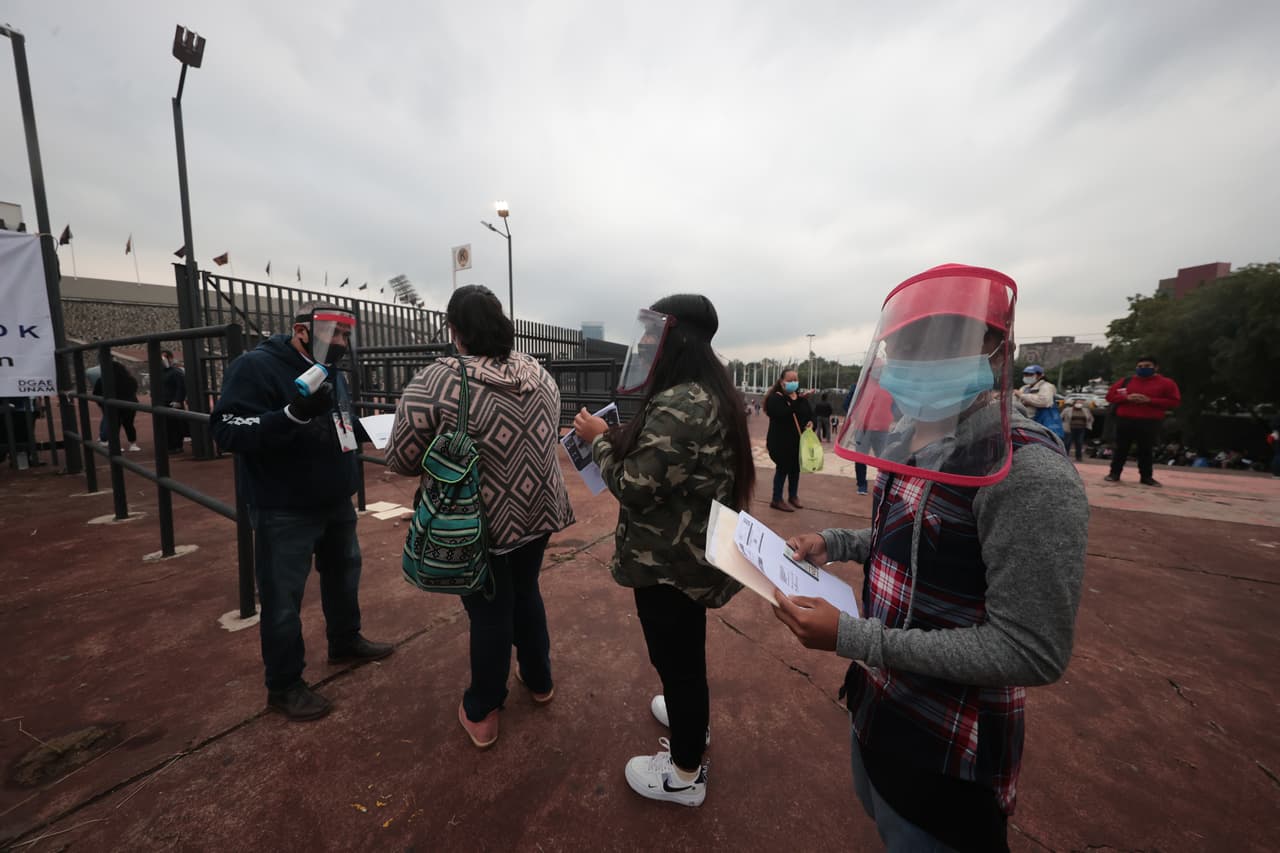 Un estudiante posa para una fotografía antes de ingresar y tomar el examen de admisión de la Universidad Nacional Autónoma de México (UNAM) en el Estadio Olímpico Universitario, este miércoles 19 de agosto. 
<b>Miles de solicitantes siguen las medidas y protocolos de higiene para combatir al <a href="https://www.univision.com/temas/coronavirus">coronavirus</a>. </b> El inmueble es una de las 25 sedes utilizadas debido al brote de la pandemia.