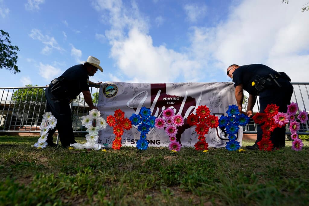 Los miembros del departamento de policía de Pharr, Texas, colocan una pancarta en una barrera cerca del memorial de la escuela.