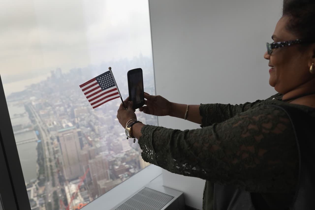 Una de las inmigrantes se toma una selfie. A lo lejos, la Estatua de la Libertad en Ellis Island. (John Moore/Getty Images)