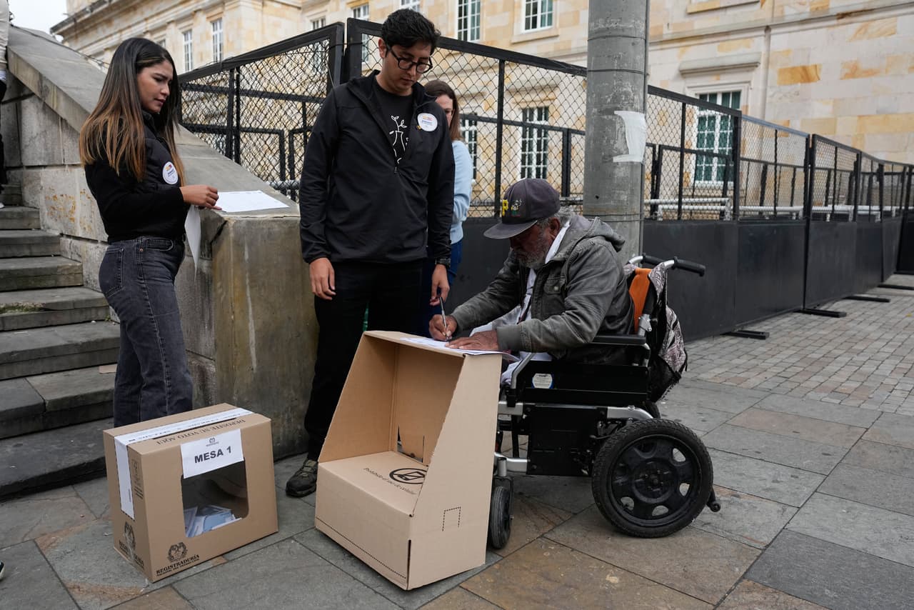 Funcionarios electorales de Bogotá llevan la casilla a pie de calle para que una persona con discapacidad pueda emitir su voto.