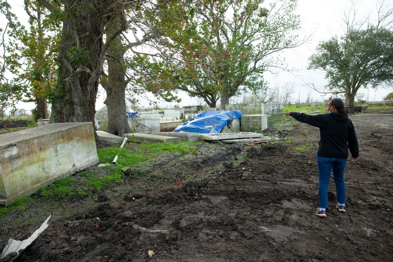 Cassandra Wilson de Ironton, Louisiana, apunta hacia el cementerio de su comunidad, que se inundó en 2021 con el huracán Ida. La marejada ciclónica empujó a los ataúdes fuera de las criptas.