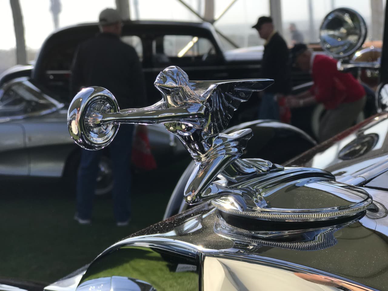 Este hermoso ornamento que muestra a una mujer alada, uno de los temas visuales más utilizados en los autos de los años 20 y 30, sosteniendo una rueda de automóvil en sus manos, corresponde a un
<b>Packard Twelve Convertible Victoria de 1933</b>.
