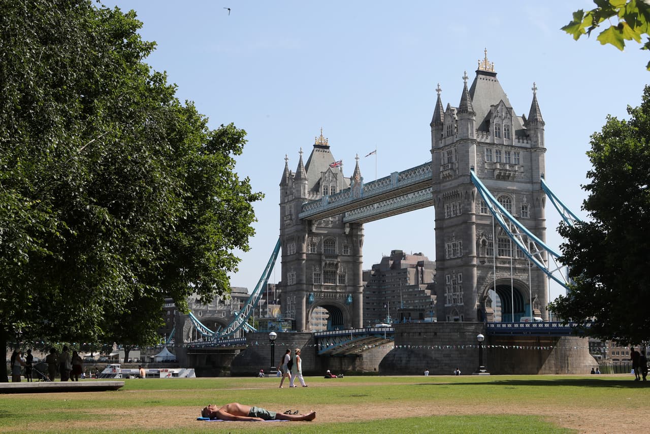 Un hombre toma el sol al lado del Tower Bridge en Londres, Inglaterra. La ciudad, típicamente templada, es la última en ser azotada por el clima inusualmente cálido y seco que ha provocado incendios forestales en toda Europa, desde Portugal hasta los Balcanes, y ha dejado cientos de muertes relacionadas con el calor.