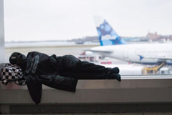 Un viajero descansa en el aeropuerto de LaGuardia, en Queens, Nueva York. Pese al viento y la nieve, los vuelos llegaban y salían como previsto este jueves.