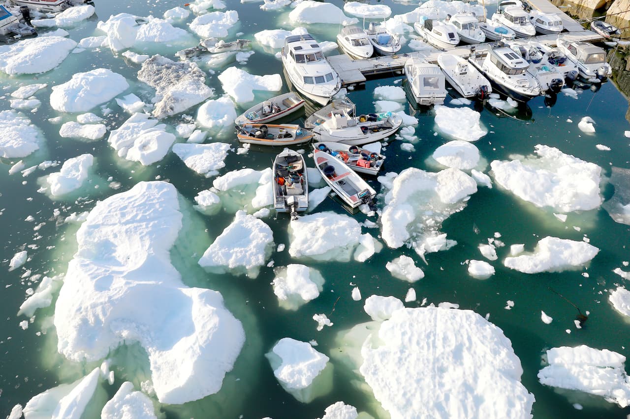 Bloques de hielo flotan junto a los barcos del puerto de Ilulissat, Groenlandia, el 2 de septiembre de 2021. La capa de hielo que cubre a la isla más grande del mundo se está derritiendo muy rápido, está elevando el nivel del mar y ha aumentado el riesgo global de inundaciones.
<br>
<br>Una investigación publicada por la revista
<a href="https://www.nature.com/articles/s41467-021-26229-4"><u>Nature Communications</u></a> el 1 de noviembre encontró que de la superficie helada de Groenlandia se derritió en términos que se elevan a 3.5 billones de toneladas (
<i>trillions</i> en inglés) de hielo entre 2011 y 2020.