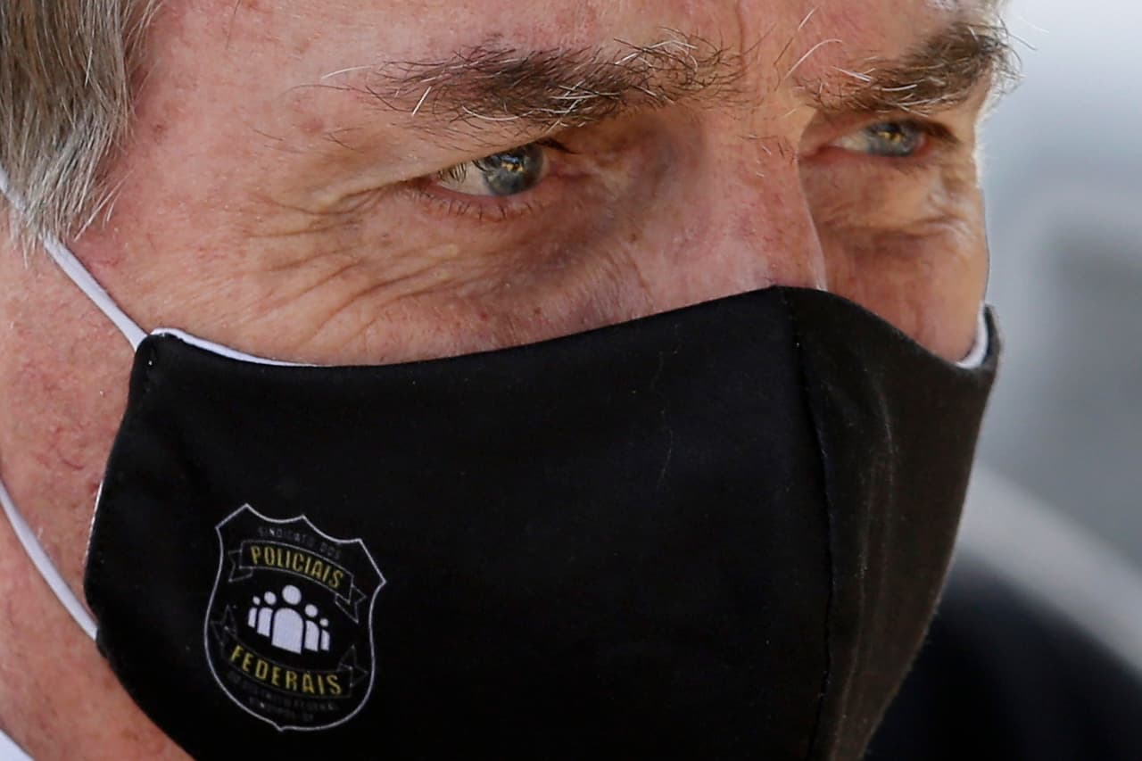 Jair Bolsonaro, presidente de Brasil, que comparó al coronavirus con una gripe, también aparece en público con mascarilla, en la imagen lo hace durante un encuentro con los medios en el palacio presidencial en Brasilia, el 26 de mayo.
