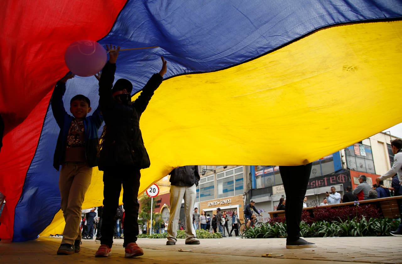 Los niños juegan bajo una bandera de Colombia durante una manifestación del Primero de Mayo en Bogotá, Colombia.