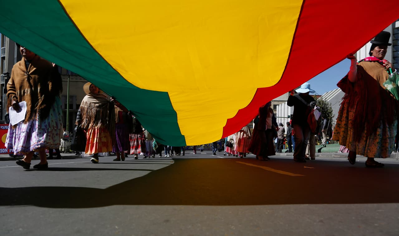 Mujeres indígenas llevan una bandera boliviana durante una marcha del Primero de Mayo en La Paz, Bolivia.