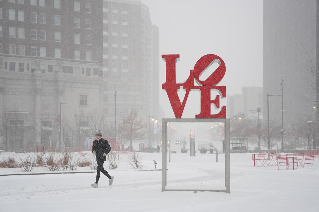 A person jogs at JFK Plaza, also knows as Love Park during a winter storm in Philadelphia, Sunday, Jan. 25, 2026. (AP Photo/Matt Rourke)