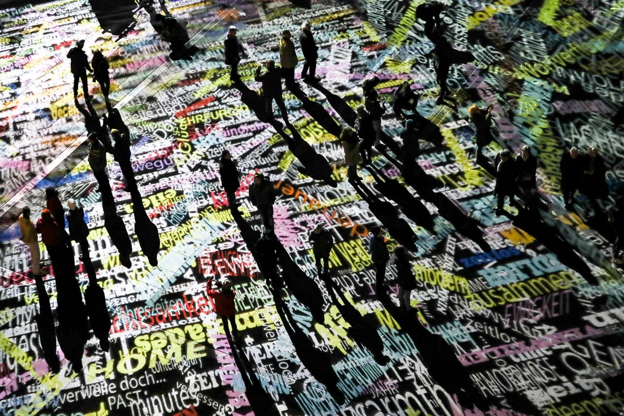 Visitantes entre palabras proyectadas en un montaje artístico frente a la catedral de Colonia, Alemania, donde el año pasado se produjeron centenares de asaltos sexuales la noche de fin de año y esta vez hay desplegados unos 1,500 oficiales de policia.