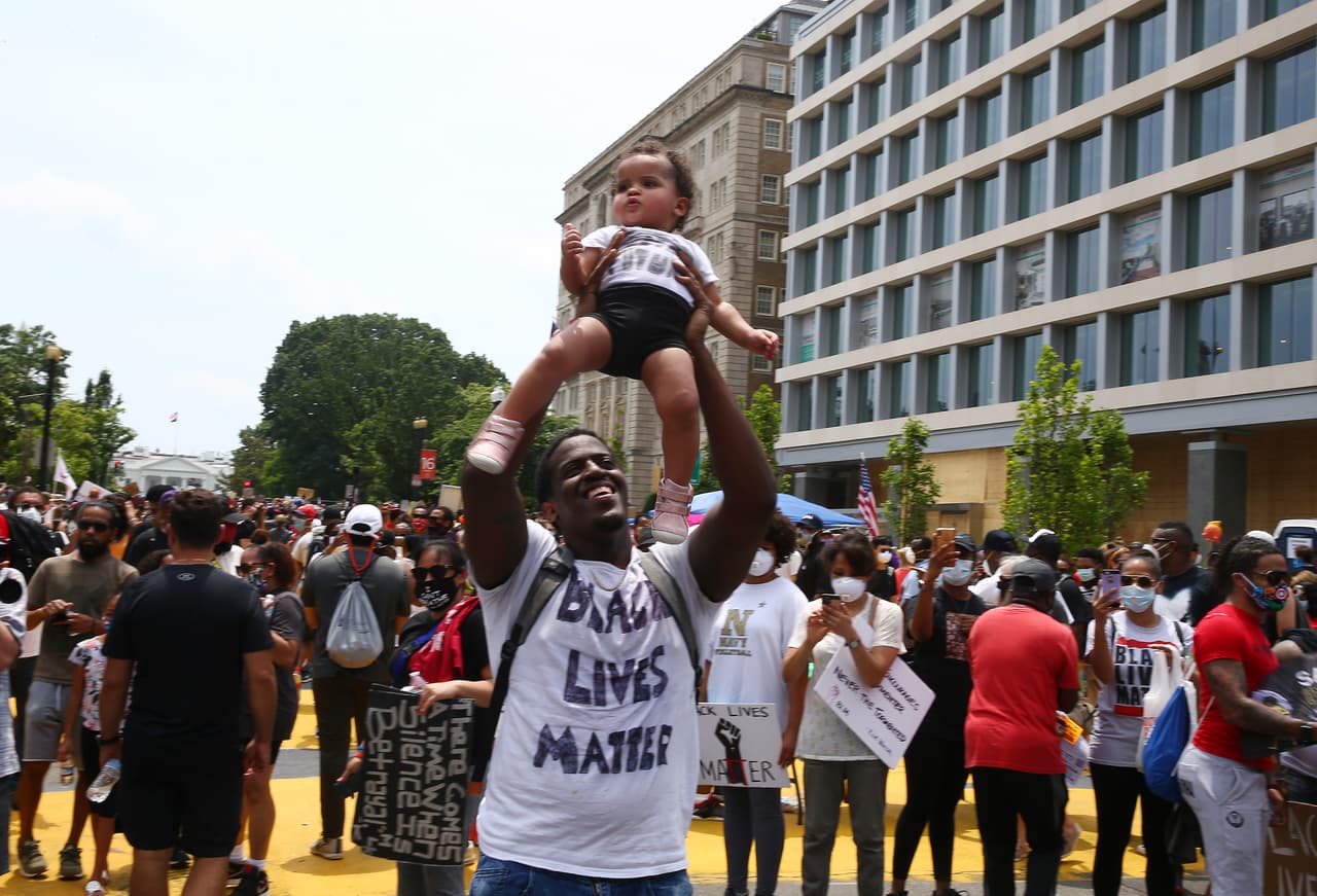 Un hombre alza a una pequeña niña en la manifestación pacífica frente a la mansión presidencial. 
<br>
<br> 
<br>