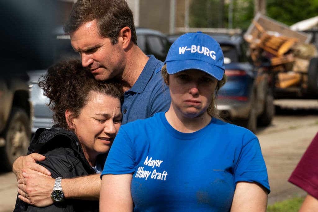 El gobernador de Kentucky, Andy Beshear, abraza a la representante estatal Angie Hatton mientras la alcaldesa de Whitesburg, Tiffany Craft, da un reporte de daños y pérdidas a los periodistas.