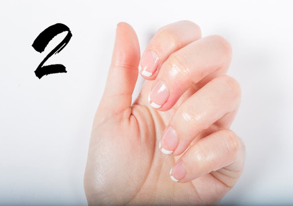 Realiza un francés tradicional y después moja en acetona un pincel biselado y abre un espacio por el centro de la uña. Puedes usar cualquier color para hacer el francés. Termina con una capa de brillo.