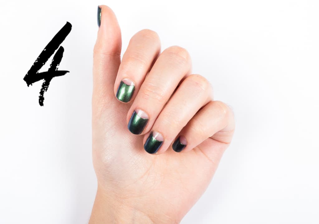 Coloca una pegatina circular en la lúnula (la parte de la uña donde se ve la luna blanca) y aplica 2 capas de tu color preferido. Retira la pegatina hacia un lado. Moja un pincel plano en acetona y corrige la imperfecciones. Sella con una capa de brillo.