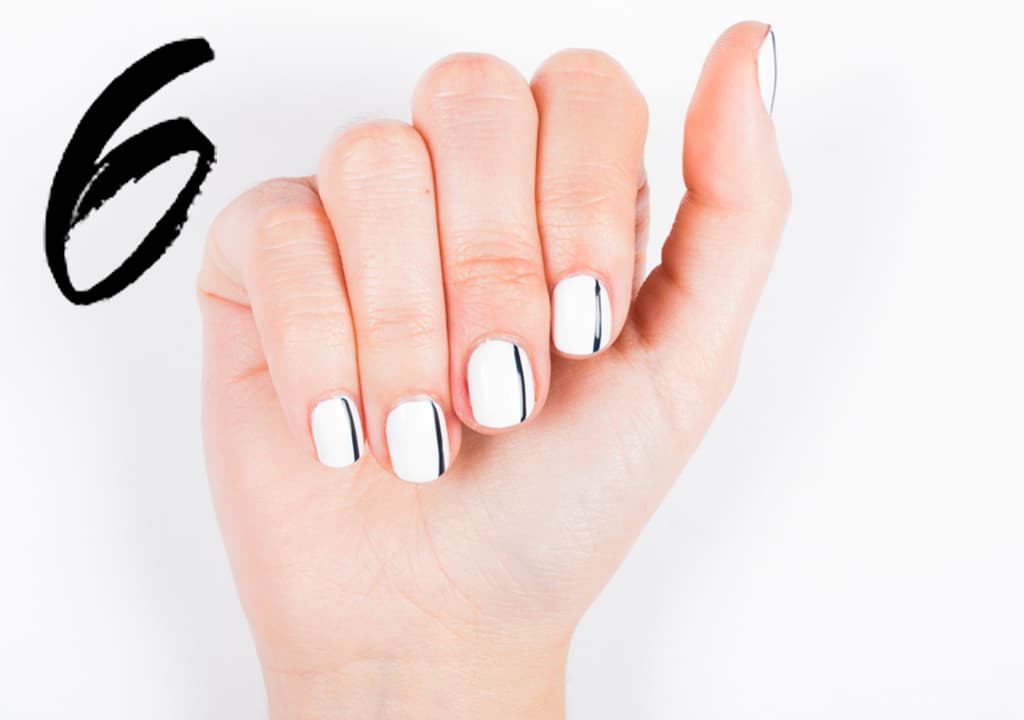 Aplica 2 capas de esmalte blanco. Con ayuda de un pincel de punta delgada traza líneas en un tono obscuro. Sella con una capa de brillo.