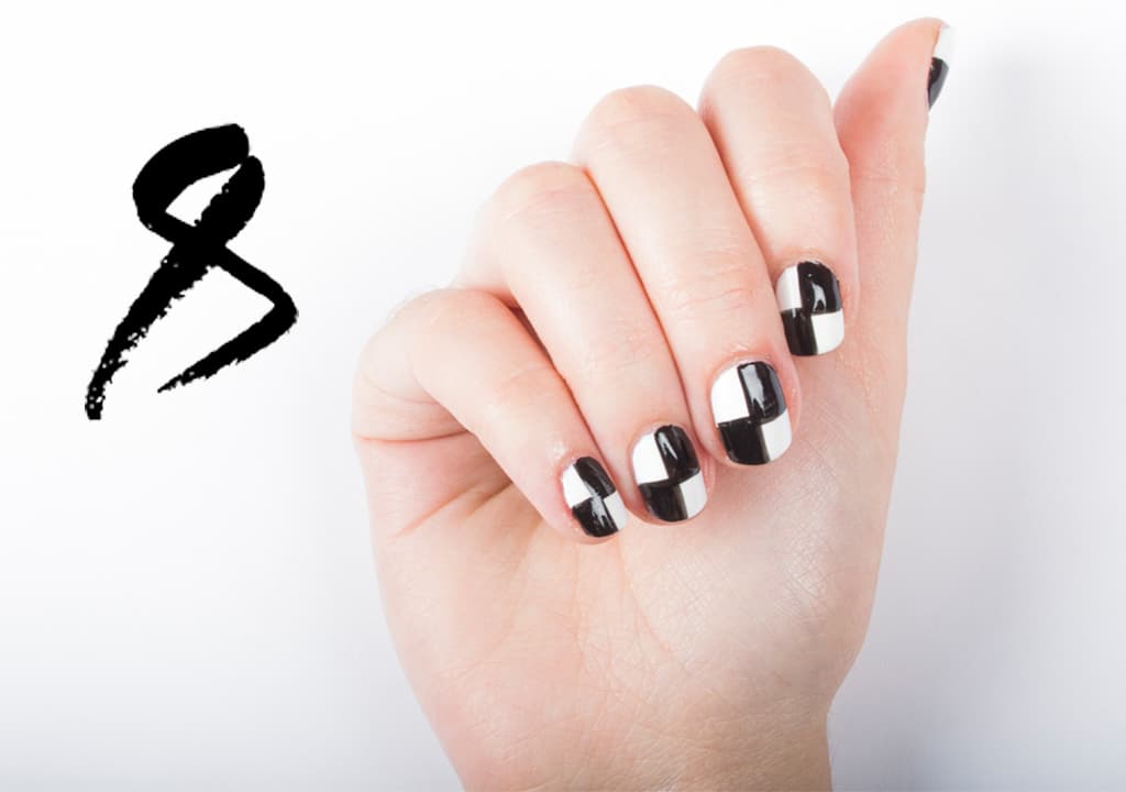 Aplica 2 capas de esmalte blanco. Con un pincel delgado traza una línea vertical y otra horizontal, con barniz negro en el centro de la uña. Rellena de negro 2 de los cuadros. Sella con una capa de brillo.