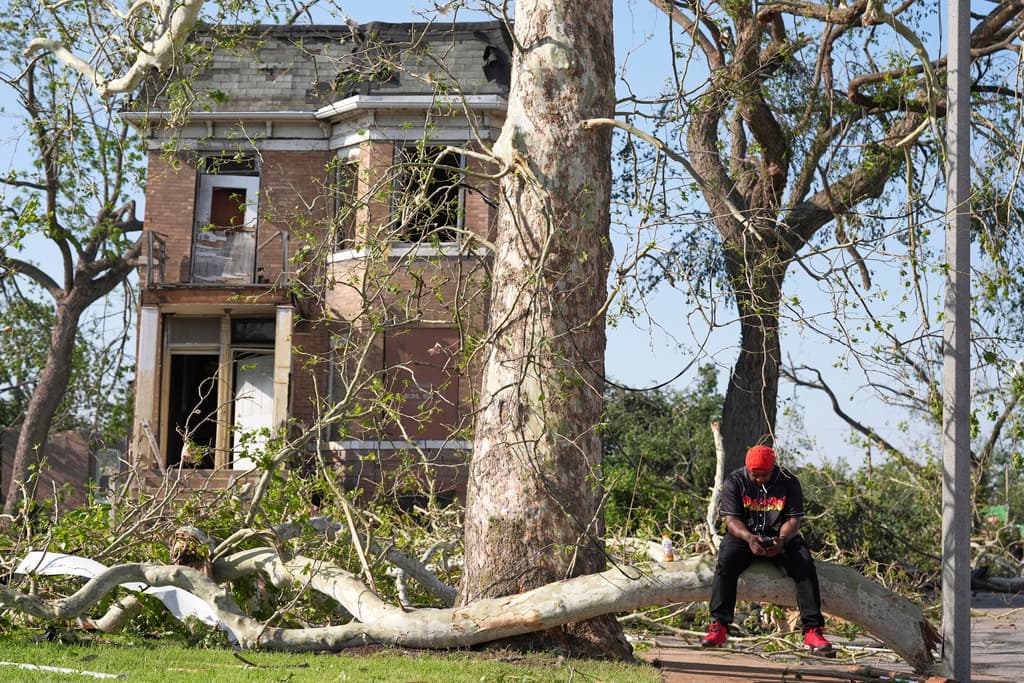 Steven Lampink se sienta en un árbol caído tras una fuerte tormenta que azotó San Luis el viernes 16 de mayo de 2025.