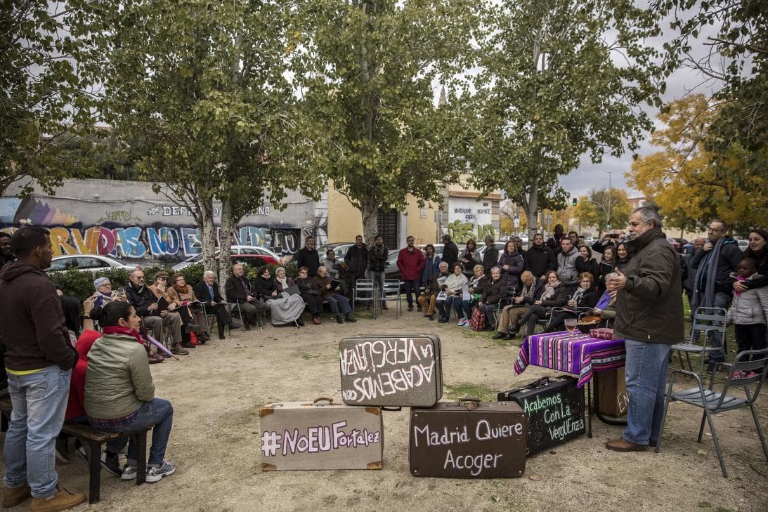 Dozens of neighbors in Entrevías, Madrid attend an outdoor mass with families being given refuge at the San Carlos Borromeo parish church. The church is packed with mattresses and suitcases, so masses are held in a nearby park.