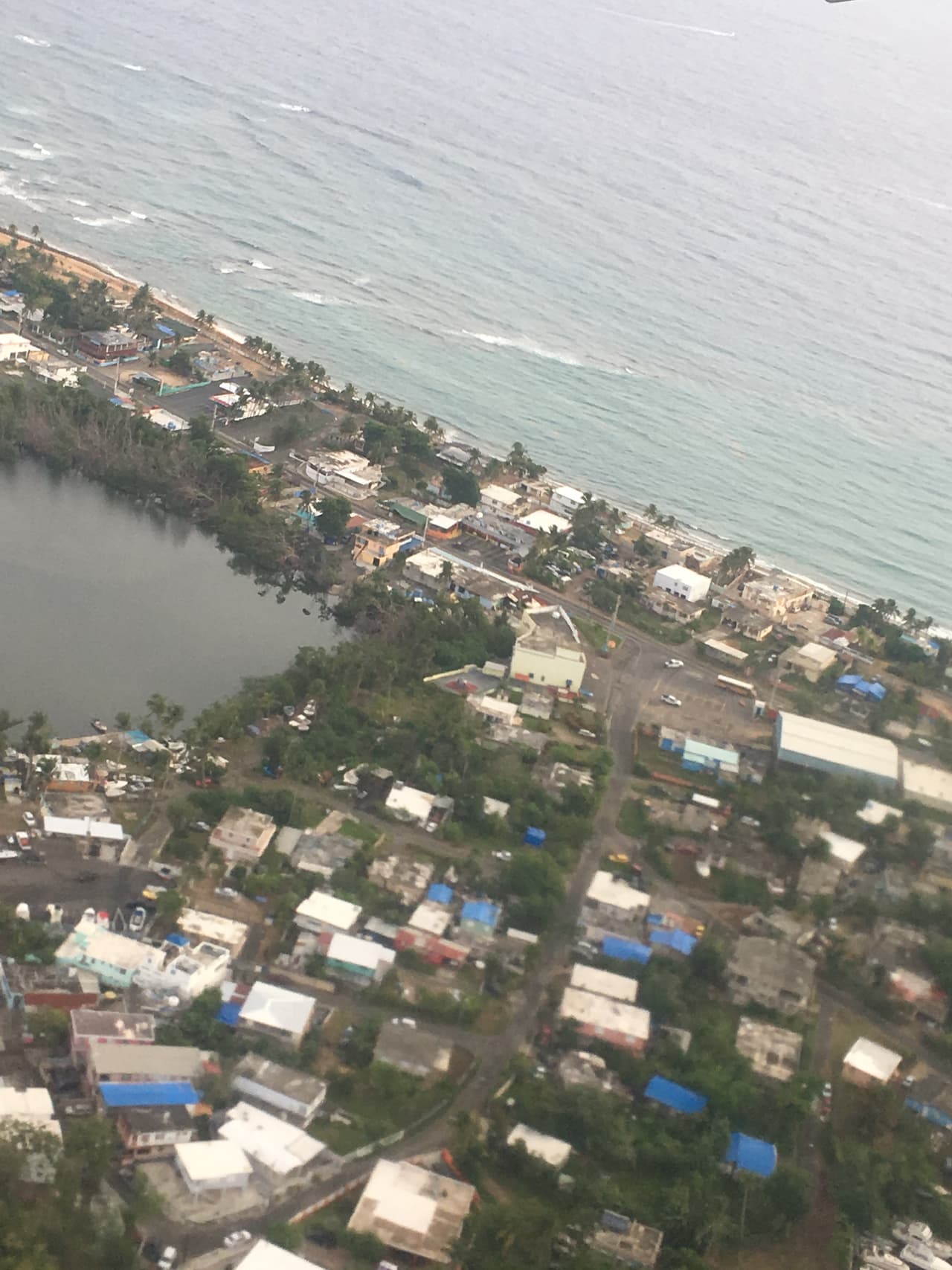 En estas imágenes puede verse desde el avión como muchas casas en el barrio de Piñones en Carolina continuan con los toldos azules de FEMA cubriendo los techos.