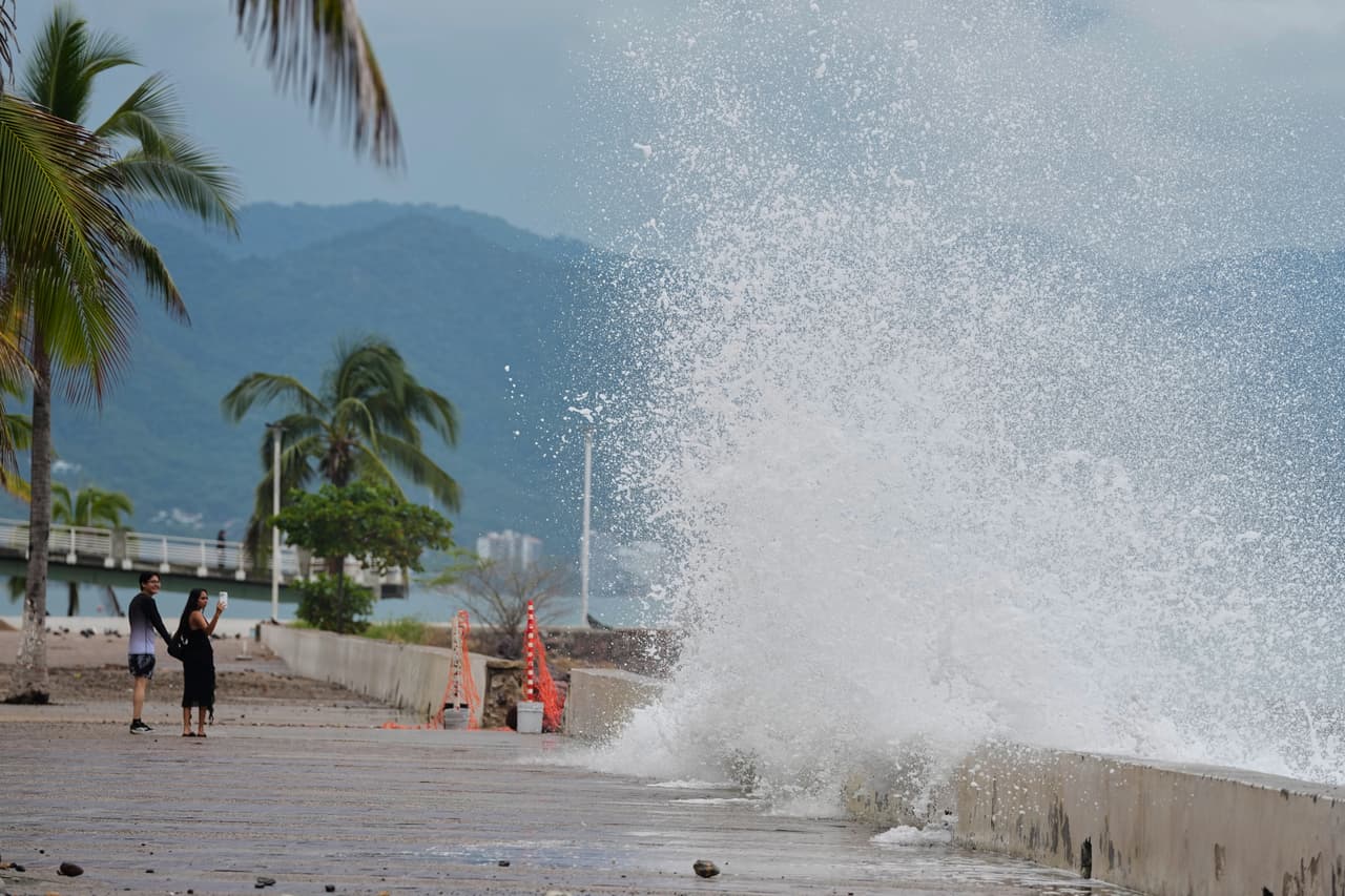 Una pareja de turistas toma fotos del fuerte oleaje que se rompe en el malecón de Puerto Vallarta, Jalisco, en la mañana del domingo.