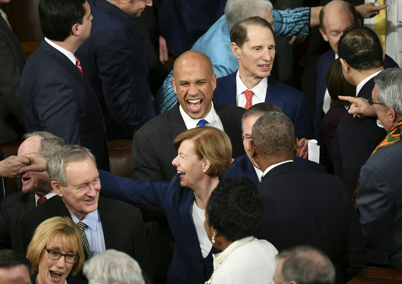 El Senador demócrata Cory Booker sonríe al saludar a algunos compañeros en la sala.