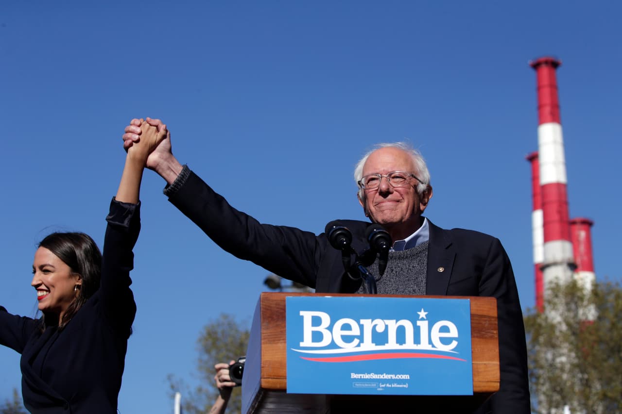 NEW YORK, NY - OCTOBER 19: Democratic presidential candidate, Sen. Bernie Sanders (I-VT) holds hands with Rep. Alexandria Ocasio-Cortez (D-NY) as she endorses him during his speech at a campaign rally in Queensbridge Park on October 19, 2019 in the Queens borough of New York City. This is Sanders' first rally since he paused his campaign for the nomination due to health problems. (Photo by Kena Betancur/Getty Images)