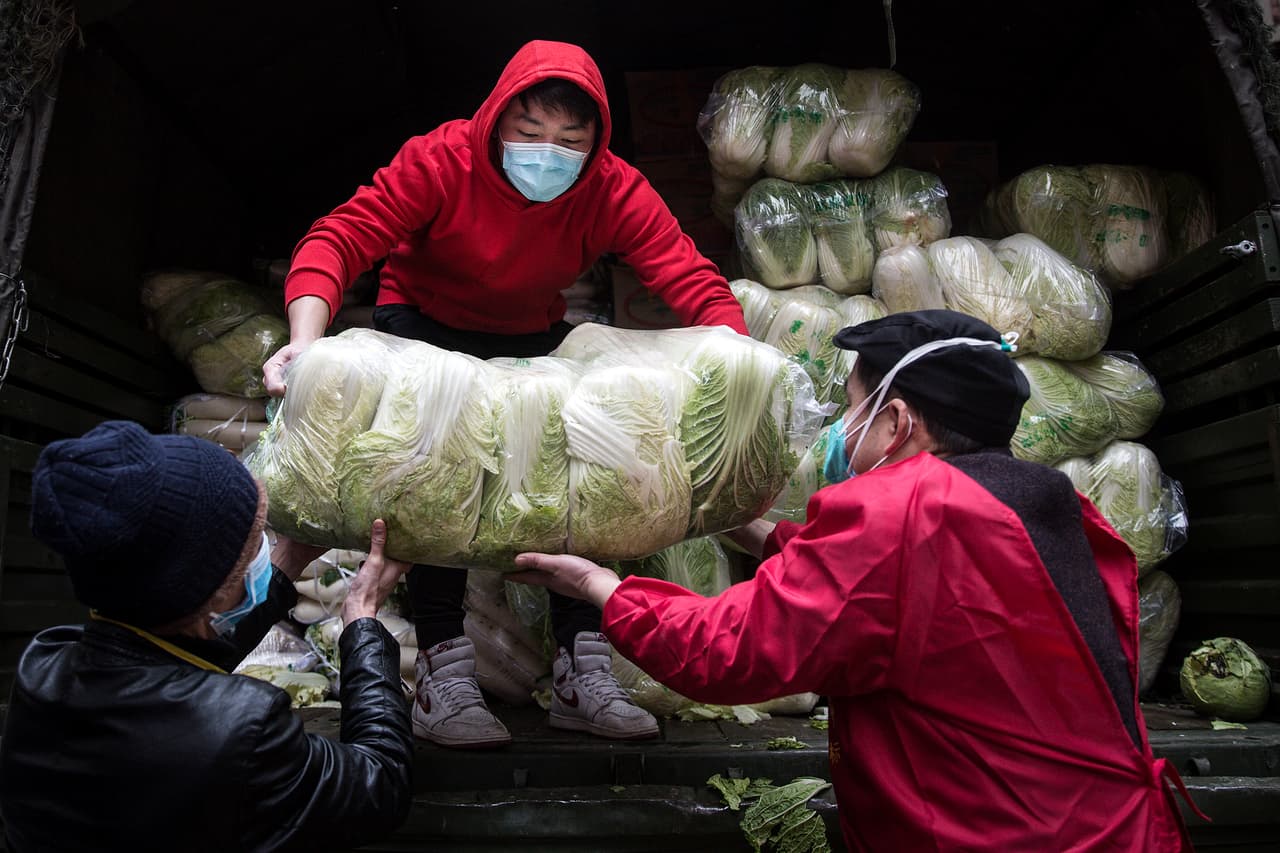 Trabajadores enmascarados descargan alimentos en un hospital de Wuhan, el epicentro de la crisis por el nuevo coronavirus. La mayoría de las compañías que anunciaron que no comenzarán a operar se encuentran en los alrededores de esta ciudad.