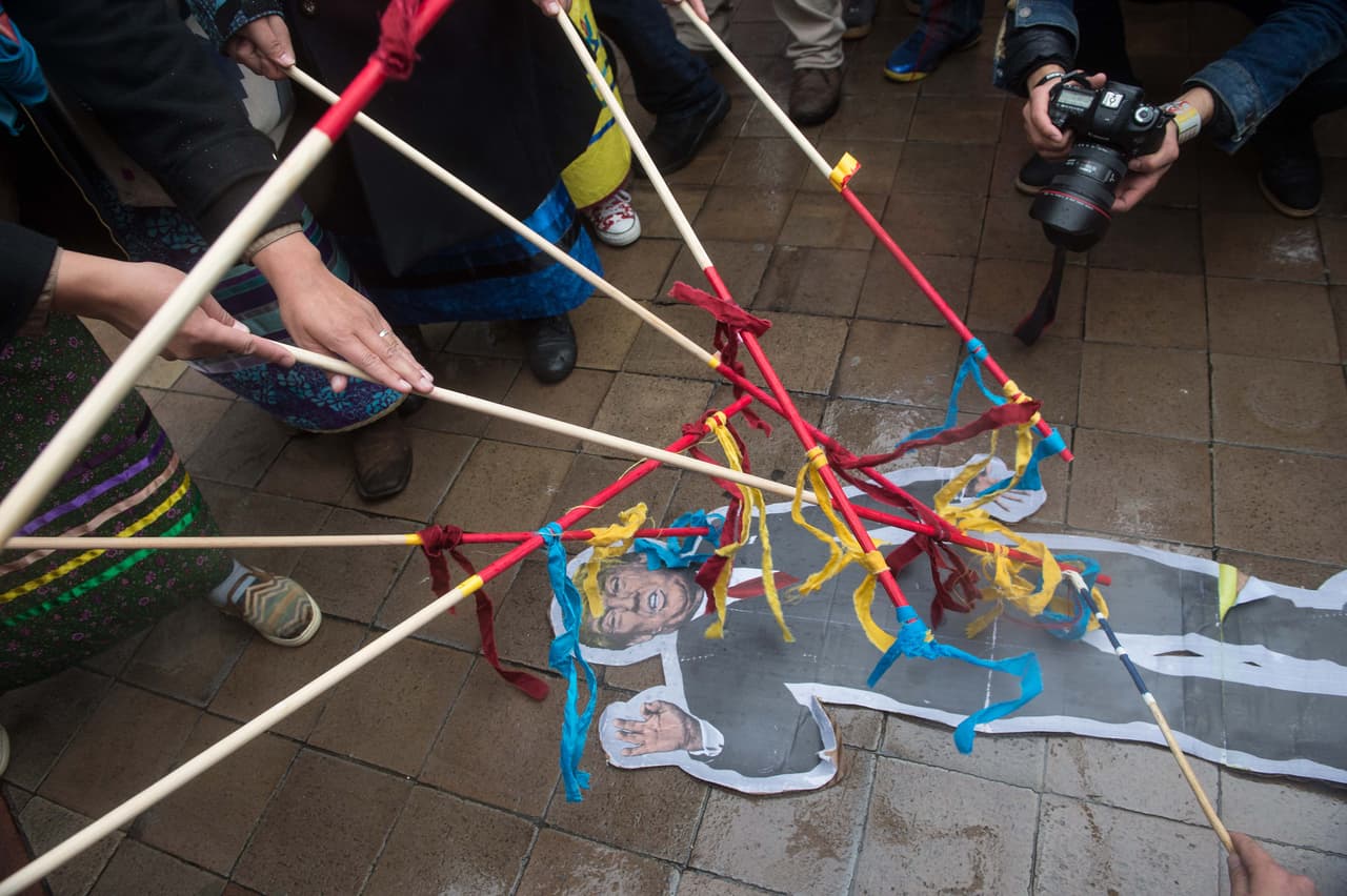 Participantes de la marcha golpean con palos a una figura recortada de del presidente Donald Trump.