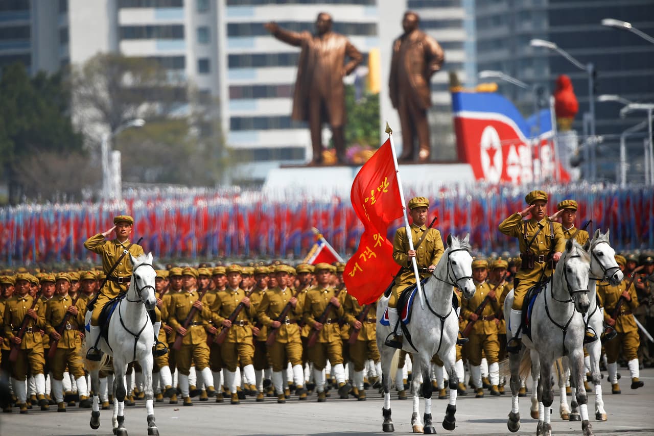 Soldados montados en caballos encabezan el desfile militar. Atrás las enormes estatuas del fundador del país, Kim Il-sung y su hijo Kim Jong-il.