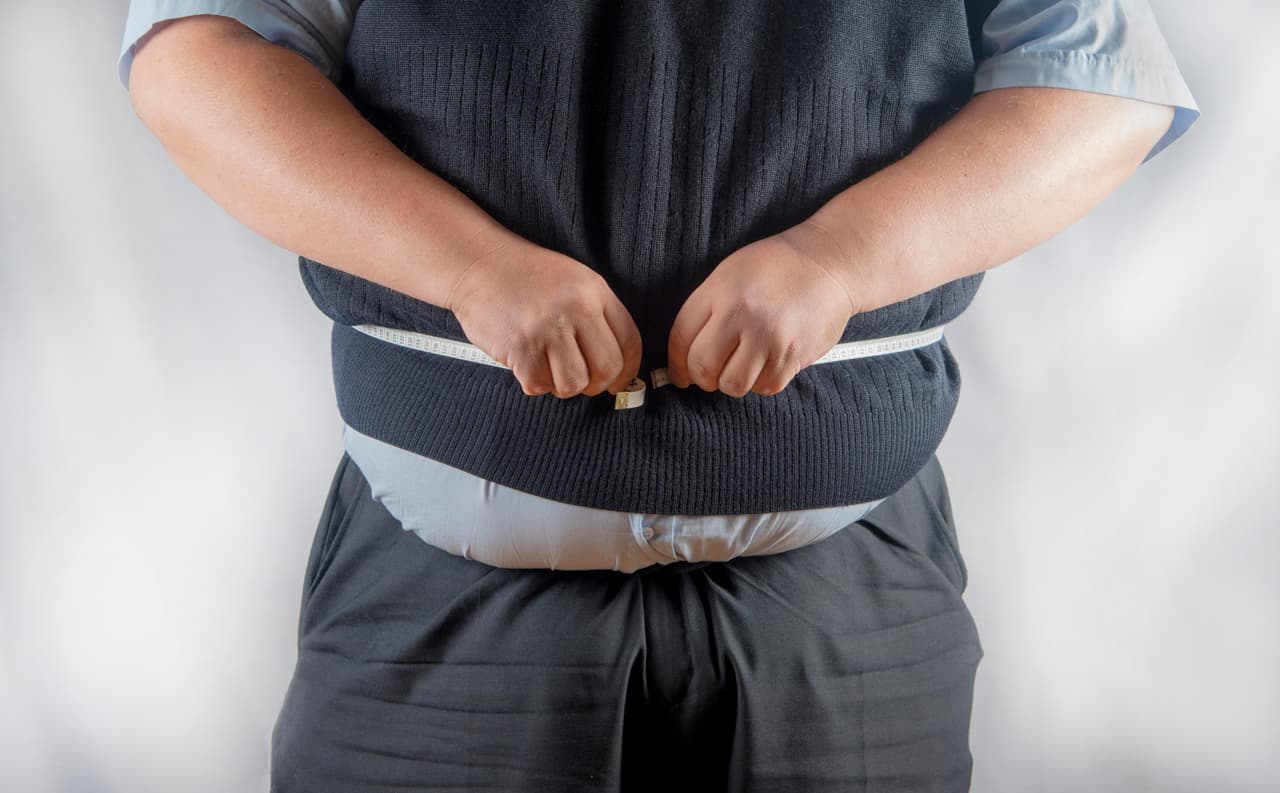 Very over weight man measuring his waist