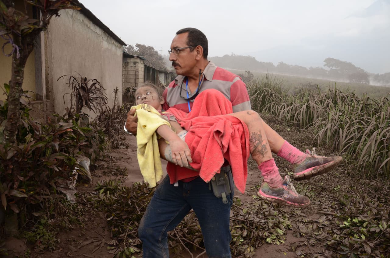 Este hombre ayuda a evacuar a las personas que han quedado damnificadas por el río de lodo y piedras que causó la erupción del volcán de Fuego en Guatemala.
